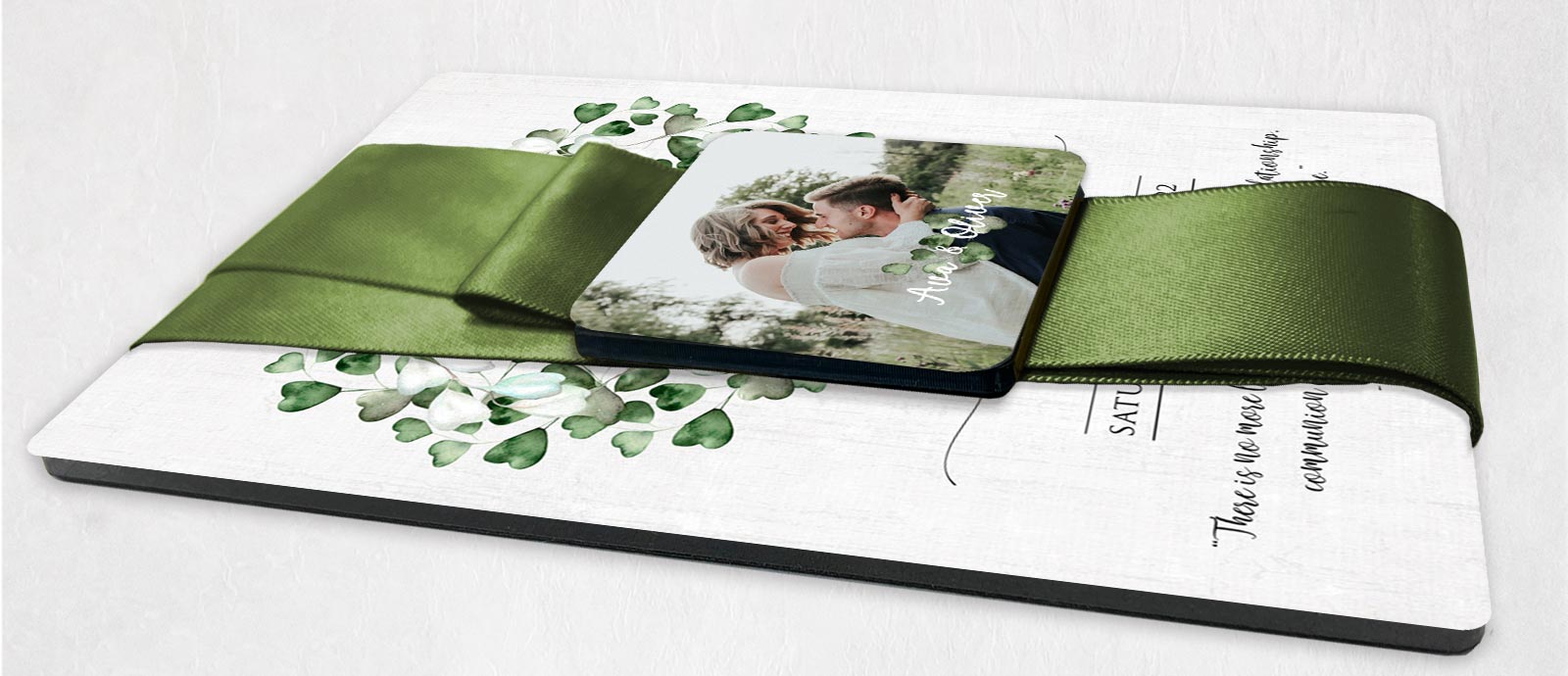 Metal wedding invitation laying down with green ribbon magnetic closure